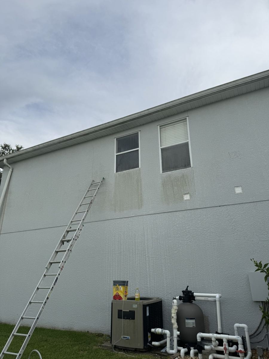 Two-story stucco wall streaked with mildew before soft washing